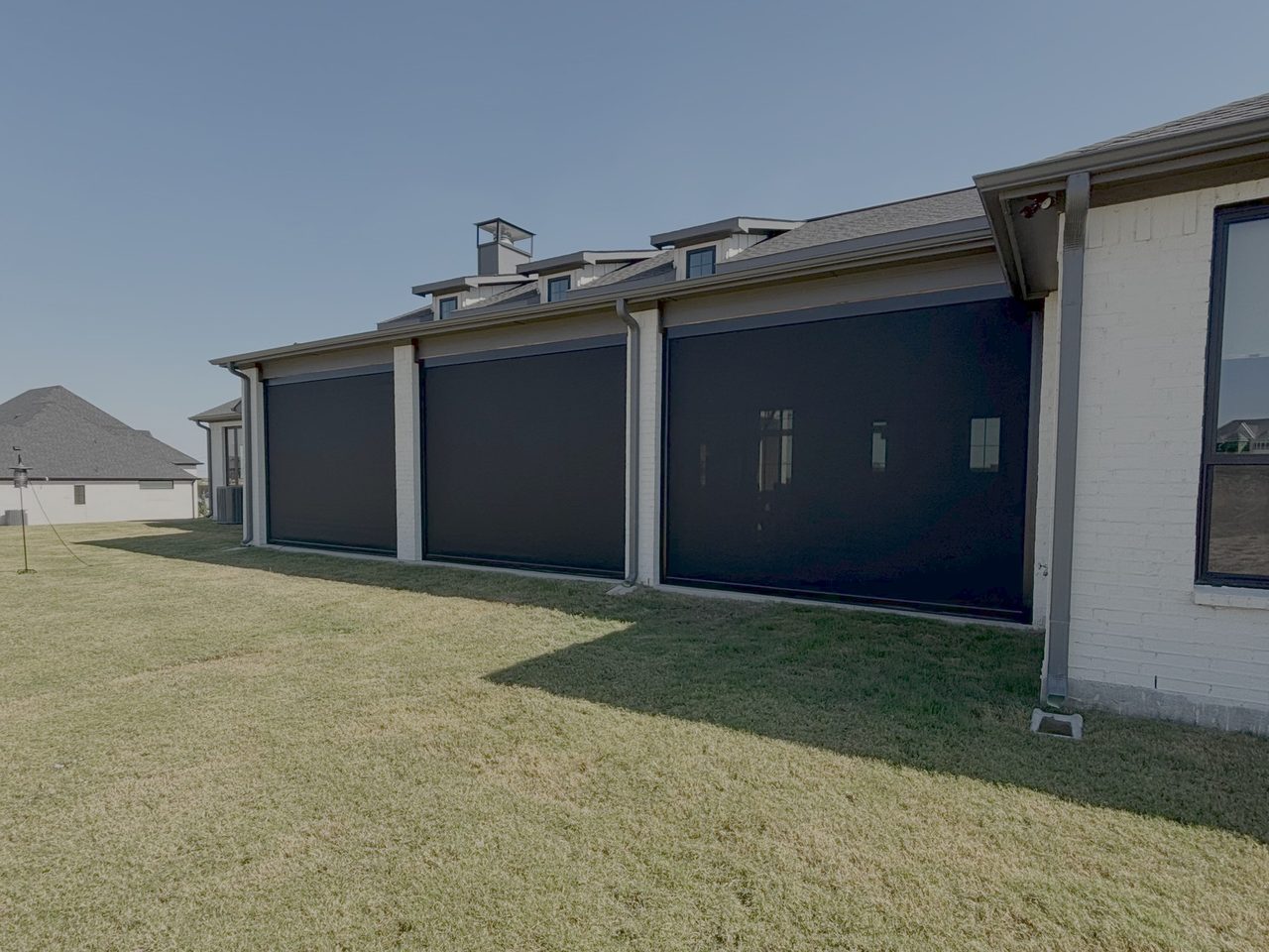 Black exterior patio shades enclosing a covered patio by Love Is Blinds