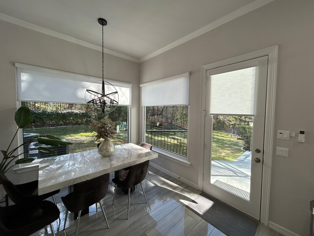 Light-filtering roller shades in a bright Iowa dining room by Love Is Blinds