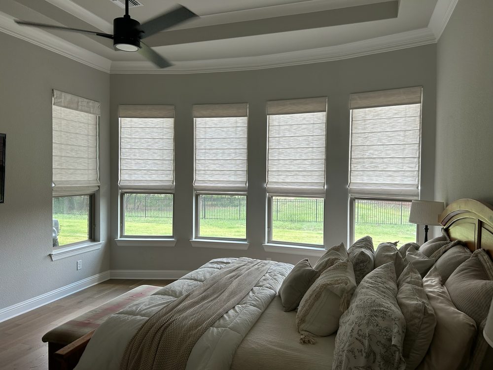 Roman shades on a bay of windows in an Iowa master bedroom by Love Is Blinds